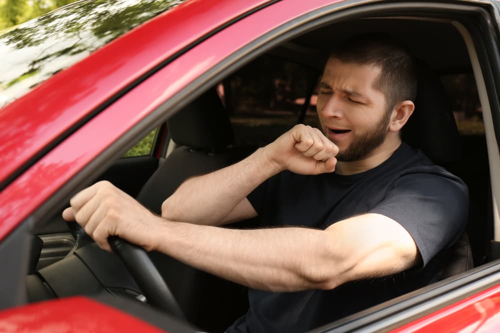 Tired man yawning while driving