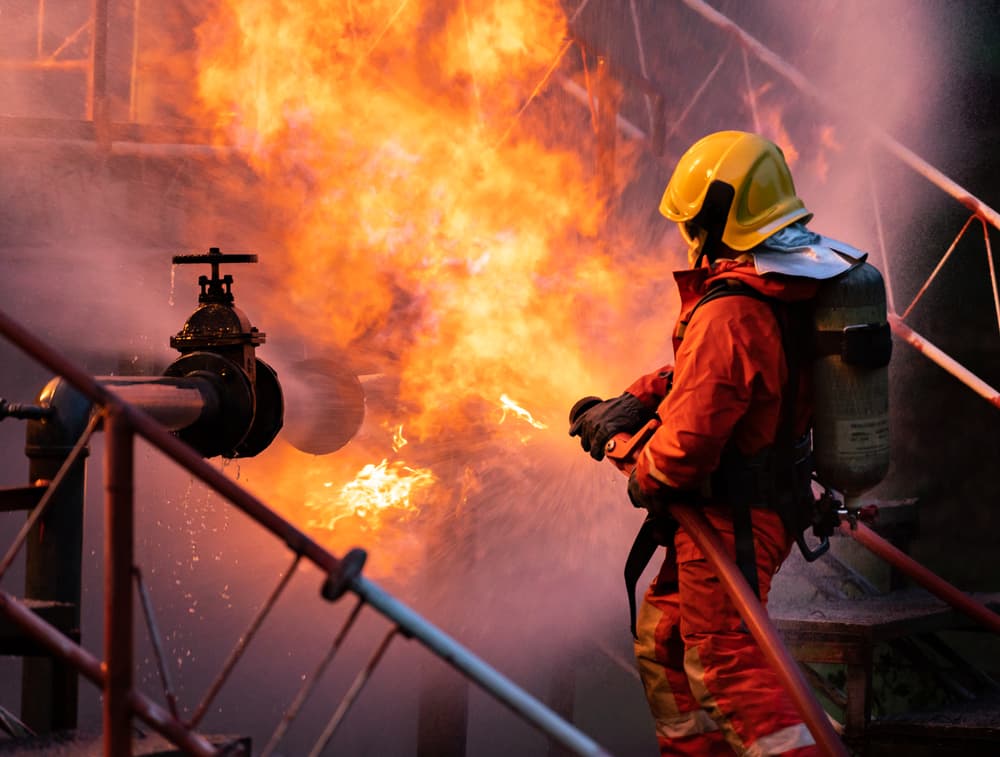 Firefighter using water to extinguish fire from oil oil rig